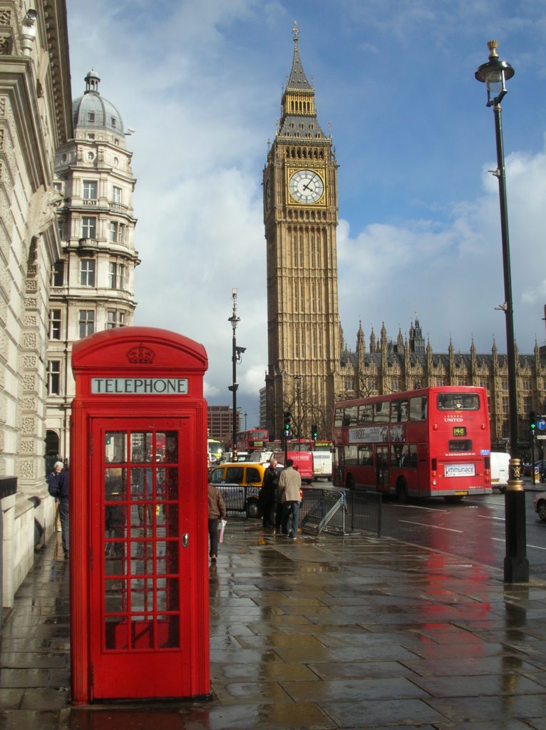 Big Ben in the background with London's iconic red public phone booth and double-decker bus